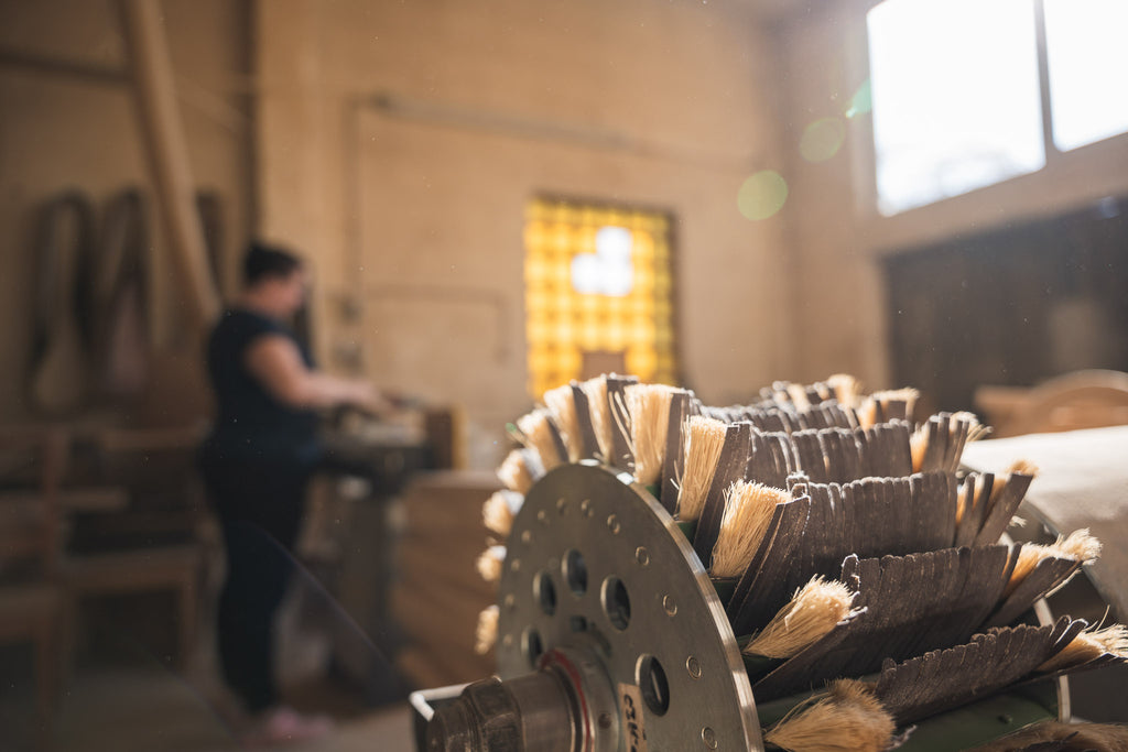 Schleifmaschine in einer Tischlerwerkstatt mit Mitarbeiterin an der Produktion von Massivholzbeinen für Esszimmertische
